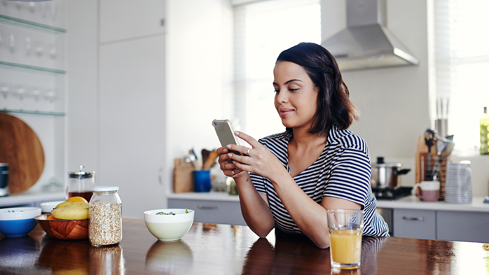 Woman in kitchen on her smartphone